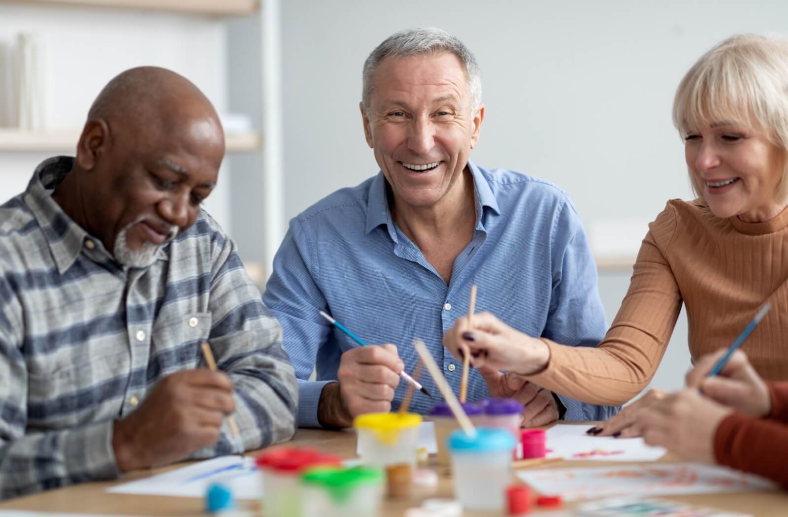 Three assisted living residents happily painting during craft night.