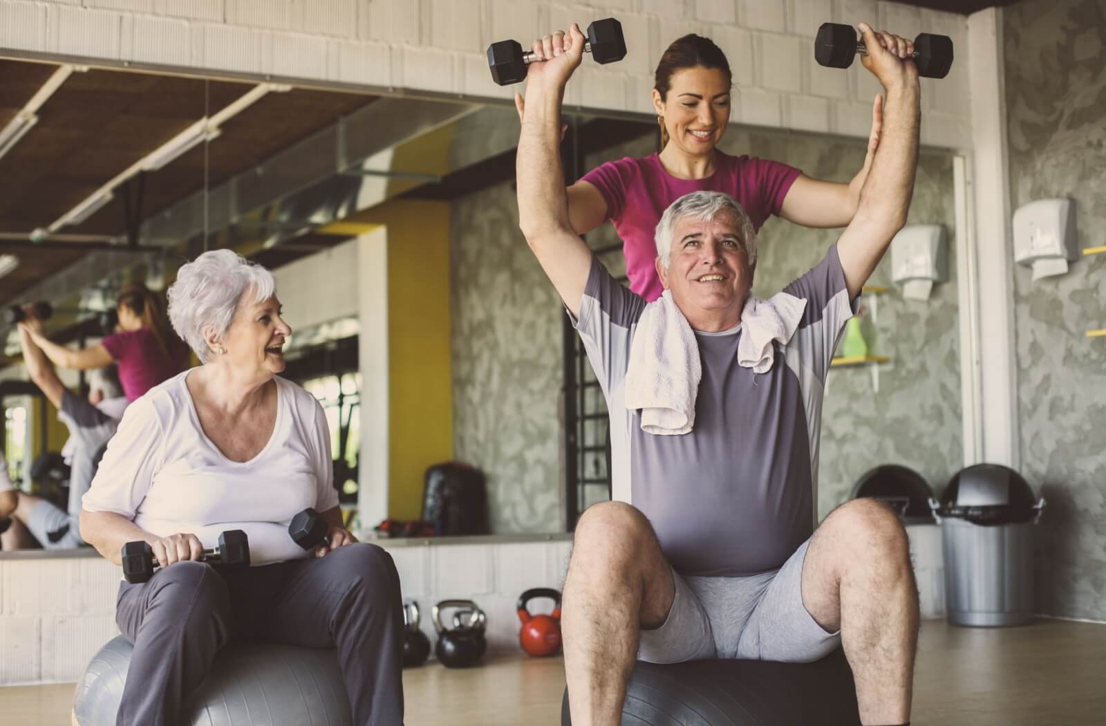 A fitness trainer guides seniors through strength training exercises using hand weights.