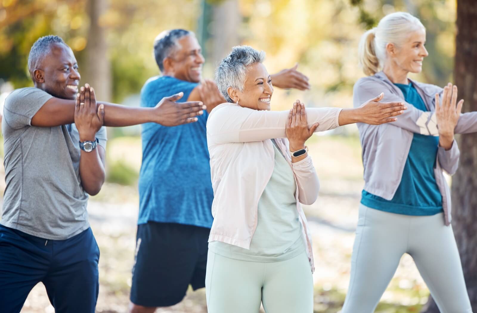 A senior fitness class exercises outside on a beautiful day in the park.