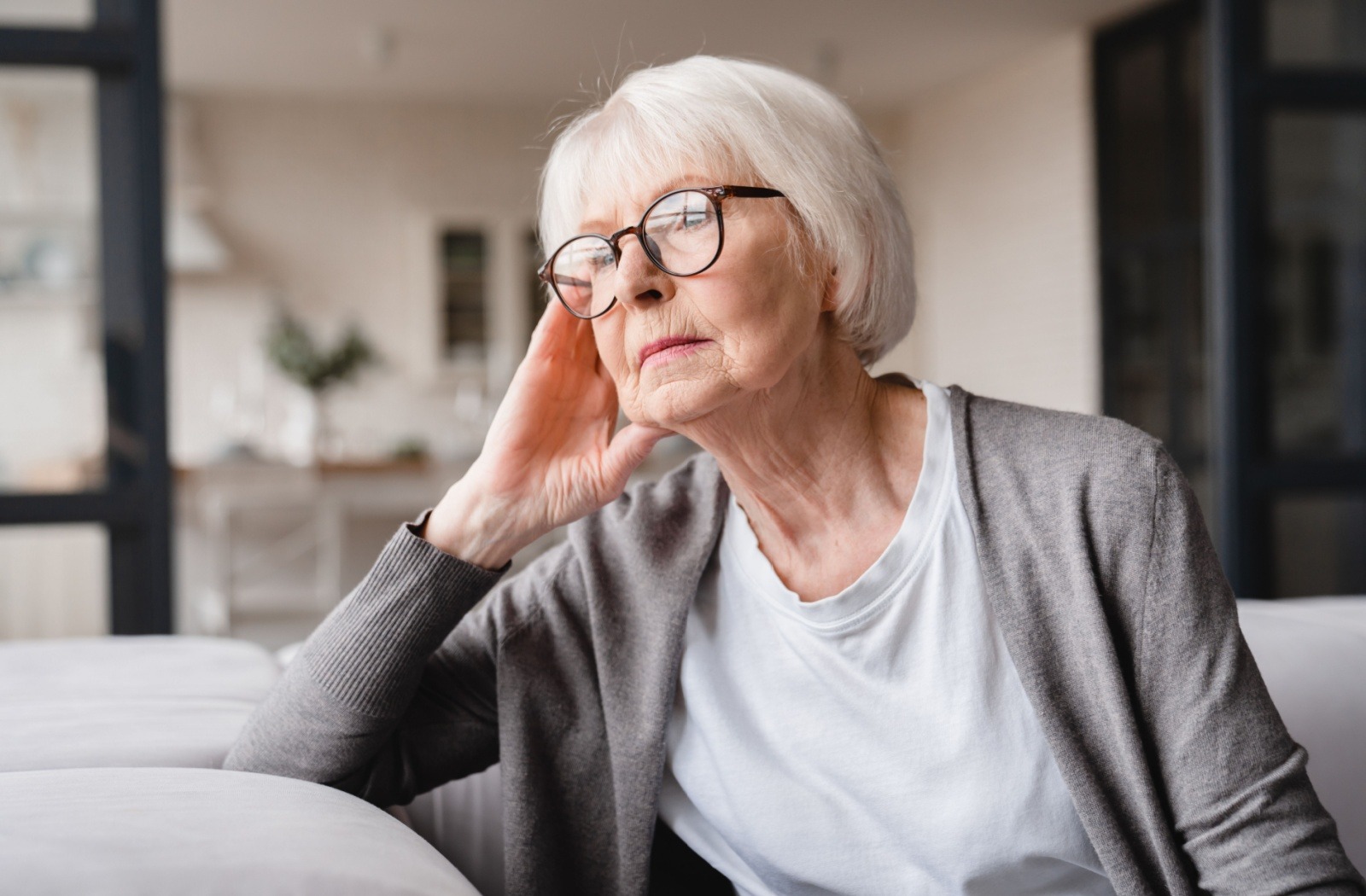 A senior spouse looks off in the distance while visiting their spouse at a memory care community.