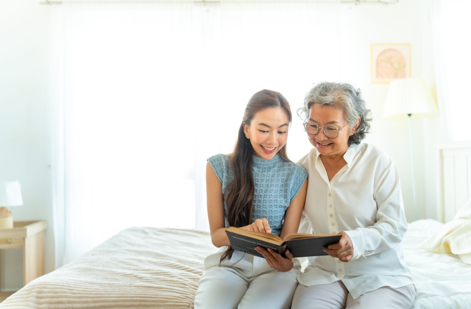 An adult child and their senior parent read through a book together